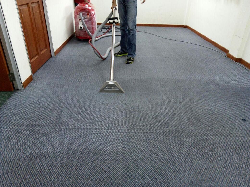 Professional technician using a hot-water extraction wand to deep clean carpet