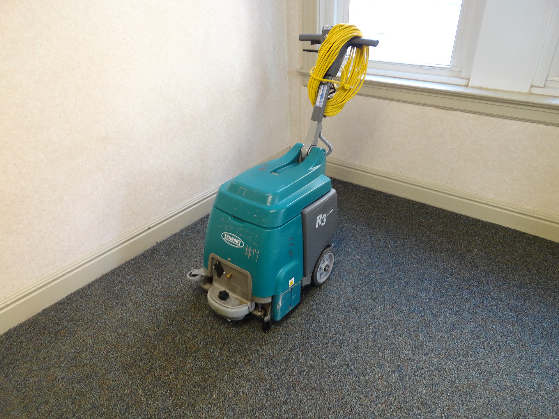 Commercial carpet cleaning machine standing on freshly cleaned office carpet