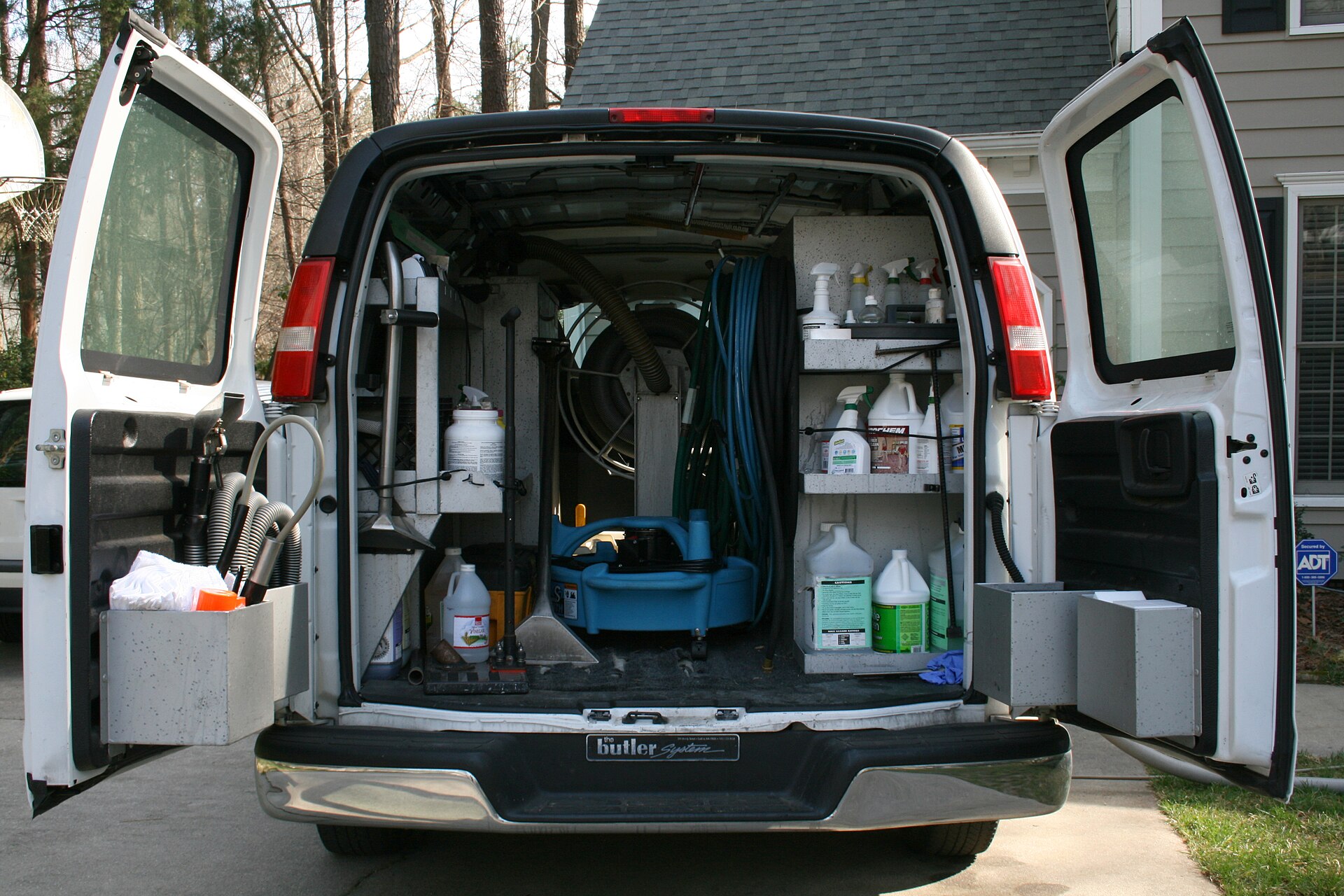 Rear of a carpet cleaning work van fitted out with hoses, wands and cleaning solutions